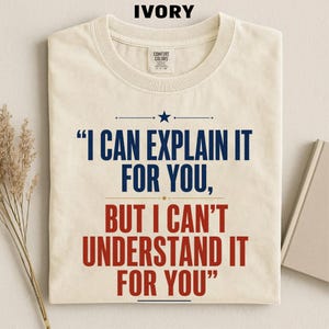 May include: An ivory crew neck t-shirt featuring the dark blue text "I CAN EXPLAIN IT FOR YOU," and the red text "BUT I CAN'T UNDERSTAND IT FOR YOU" with a small blue star above the text and a Comfort Colors brand label at the neckline.