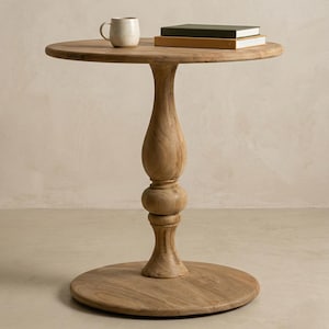 May include: A light brown wooden side table with a round top and a decorative pedestal base. A small, off-white mug and two books are on the tabletop. The table is approximately 71 cm tall.