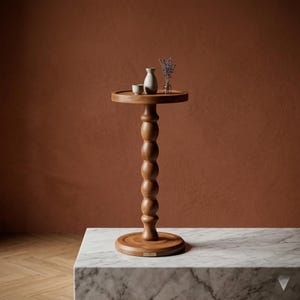 Könnte beinhalten: Ein Beistelltisch aus Holz mit runder Ober- und Unterseite, verbunden durch eine gedrehte, kugelgestapelte Säule. Der Tisch trägt eine kleine weiße Vase, zwei kleine Tassen und eine kleine Glasvase mit getrocknetem Lavendel.