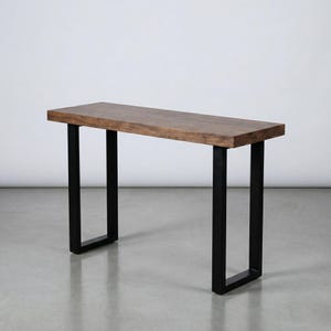 May include: A rectangular wooden console table with a dark brown finish. The table is supported by black, U-shaped metal legs. The table's design is minimalist and modern, suitable for entryways or living spaces.