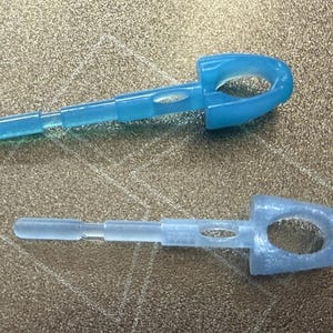 May include: Two small, elongated plastic components with a rounded, hollow head and a stepped, cylindrical body. One component is a vibrant, translucent blue, while the other is a pale, semi-transparent, frosted white or light grey colour.