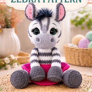 May include: A crocheted zebra pattern with the text "Adorable Crochet ZEBRA PATTERN". The zebra is white and gray with pink accents and large, expressive eyes. The pattern includes step-by-step instructions, detailed instructions, a printable PDF, and photos.