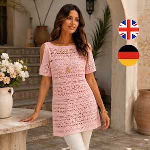 May include: A light pink crochet top with short sleeves and shoulder cutouts. The top has a round neckline and a detailed openwork pattern. A gold-colored pendant hangs from a delicate chain. The model is wearing white pants.