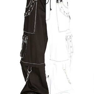Op de afbeelding: Zwart-witte gespleten cargobroek met witte stiksels en zilveren kettingaccenten. De broek heeft meerdere zakken, bandjes en een taille met trekkoord. De broek wordt gedragen met zwarte laarzen.