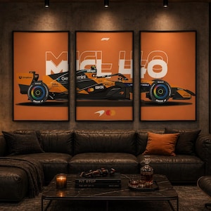 以下が含まれることがあります： オレンジ、黒、青色のマクラーレンF1レーシングカーが描かれた3つの額入りポスター。モダンなリビングルームの黒い革張りのコーナーソファの上に展示されています。「McLaren」の文字はネオンです。