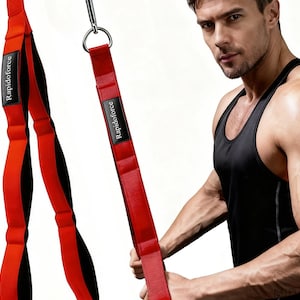 May include: Red and black exercise straps with the text "Rapidoforce" on a black label. The straps are attached to a metal ring. A person is holding the straps, wearing a black tank top.