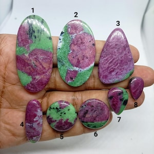 Può includere: Otto cabochon in rubino zoisite lucidati di varie forme e dimensioni, numerati da uno a otto. Ogni pietra presenta un distinto motivo maculato di inclusioni di rubino magenta-rosa vibrante su una matrice di zoisite verde lime brillante.