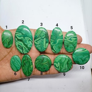 Pode incluir: Dez cabochões de malaquita verde polida de várias formas e tamanhos, rotulados com os números de um a dez. Cada pedra exibe um padrão distinto de faixas verde-claras e escuras, com um acabamento de superfície liso, brilhante e reflexivo.