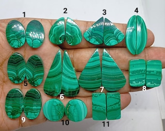 May include: A collection of eleven pairs of polished malachite gemstones in various shapes including oval, teardrop, and rectangular forms. Each pair features distinct green banded patterns and is labeled with numbers one through eleven.