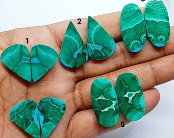 May include: Five pairs of polished malachite gemstones labeled 1 through 5. Each pair features distinct green banding and swirling patterns. The stones are shaped as teardrops, ovals, and triangles, showcasing natural mineral variations.