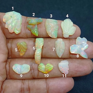 May include: A collection of eleven carved opal gemstones in various leaf and floral shapes. The opals display iridescent colors of green, yellow, and white. Each gemstone is unique, with intricate details and textures.