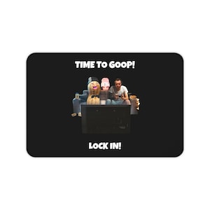Puede incluir: Alfombrilla de ratón rectangular negra con el texto "TIME TO GOOP!" en la parte superior y "LOCK IN!" en la parte inferior. La imagen presenta a una persona y dos cacahuetes antropomórficos viendo la televisión. Una botella y aperitivos están a los lados.