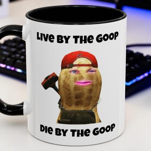 Puede incluir: Taza de cerámica blanca con interior y asa negros. La taza presenta un personaje de cacahuete con gorra roja y un martillo, con el texto "Live By The Goop, Die By The Goop".