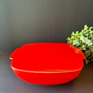 May include: A bright red, square-shaped storage container with a matching lid. The container features integrated side handles and a smooth, glossy finish. The lid sits securely on top, creating a uniform red appearance for the entire kitchen item.