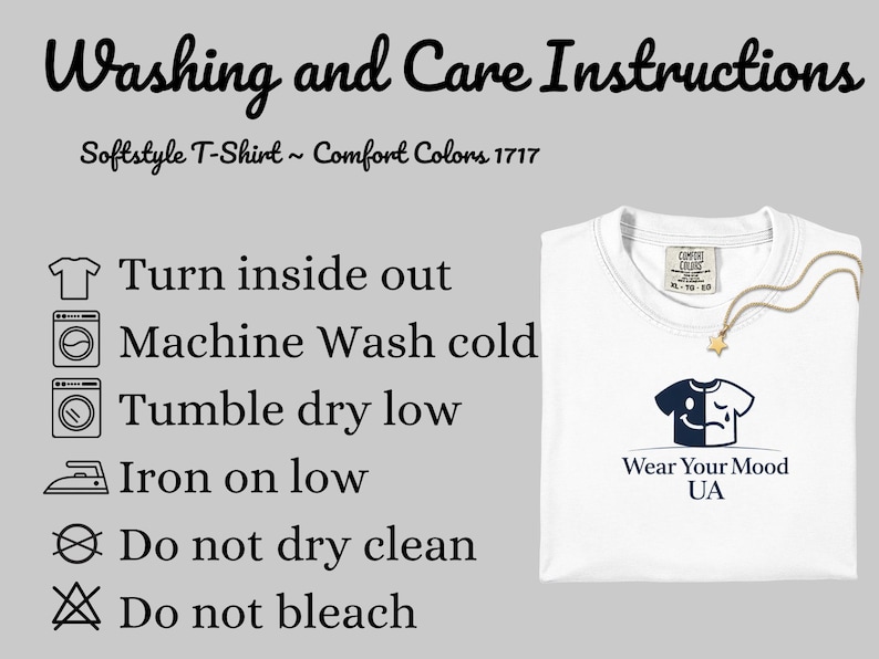 Op de afbeelding: Wit T-shirt met ronde hals, met een afbeelding van een lachend en huilend gezicht. De afbeelding bevat wasvoorschriften en de tekst "Wear Your Mood UA". Het shirt heeft een "Comfort Colors" label. De tekst "Washing and Care Instructions" is ook zichtbaar.