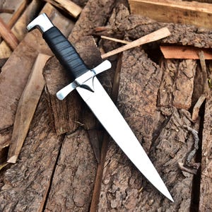 May include: A dagger with a polished steel blade and a black leather-wrapped handle. The dagger features a crossguard and a silver-colored pommel. The blade is approximately 10 inches long.