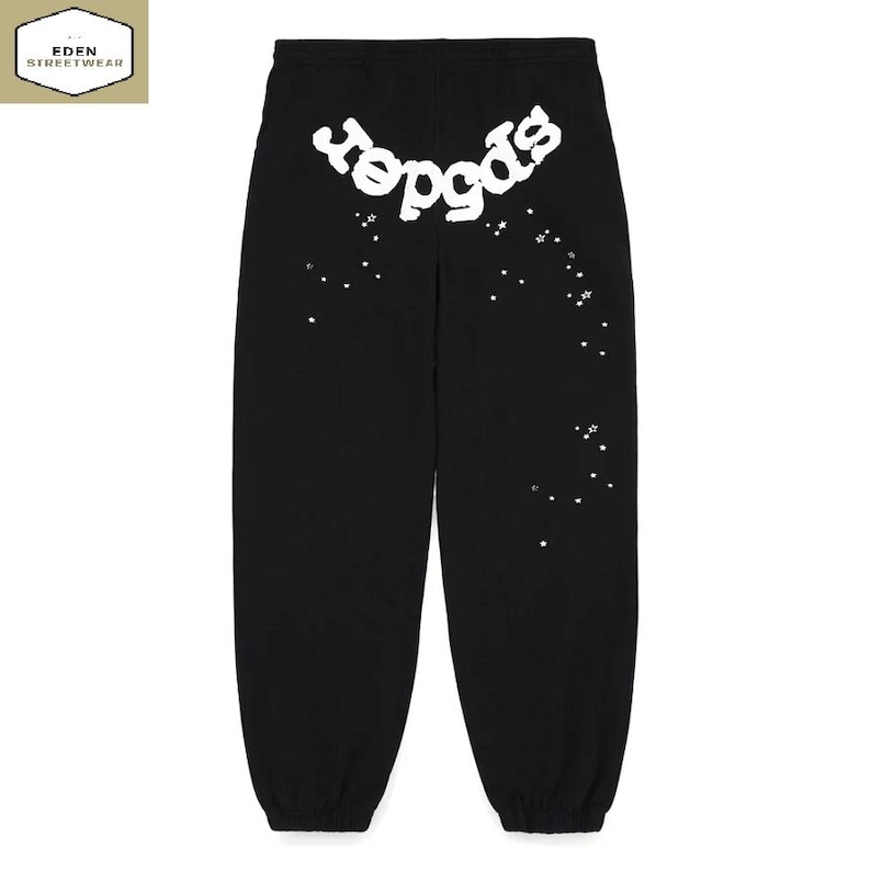 May include: Black sweatpants with the word "spider" in white, stylized text across the upper back. White star-shaped accents are scattered down the right leg. The Eden Streetwear logo is in the upper left corner.