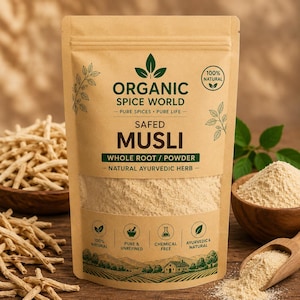 Op de afbeelding: Een beige stazak van Organic Spice World Safed Musli hele wortel en poeder. Het etiket bevat groene tekst, bladiconen en vier ronde badges met de vermelding 100% natuurlijk, puur en ongeraffineerd, chemievrij en Ayurvedisch & natuurlijk.