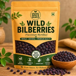 May include: A tan packet of "WILD BILBERRIES" with the text "ORGANIC SPICE WORLD" and "100% ORGANIC". A wooden bowl filled with bilberries is next to the packet, with some berries scattered on the wooden surface. The text "From Nature, For Wellness" is also visible.