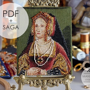 May include: A cross-stitch portrait of a woman in a red and gold dress, displayed on a decorative easel. The artwork features intricate details and is set against a green background. Text on the image reads "PDF + SAGA" and "MANSARDA cross stitch".