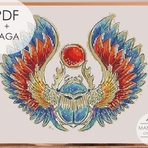 May include: A cross stitch pattern featuring a central blue scarab beetle with large, expansive wings in shades of red, orange, yellow, and blue. A red circular sun disk sits above the beetle. The image includes the text PDF + SAGA.