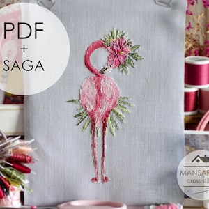 May include: A cross-stitch pattern featuring a pink flamingo with a floral headdress and green leaves. The text "PDF + SAGA" is in a white circle on the left. The Mansarda Cross Stitch logo is on the bottom right.