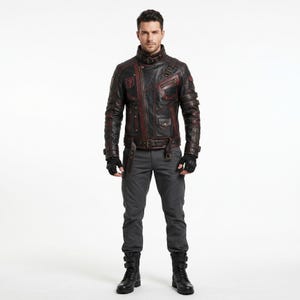Puede incluir: Una chaqueta de cuero negra con detalles en rojo oscuro, que presenta un cuello alto con hebilla, múltiples bolsillos con cremallera y un cinturón en la cintura. La chaqueta se combina con pantalones gris oscuro, botas negras y guantes sin dedos.