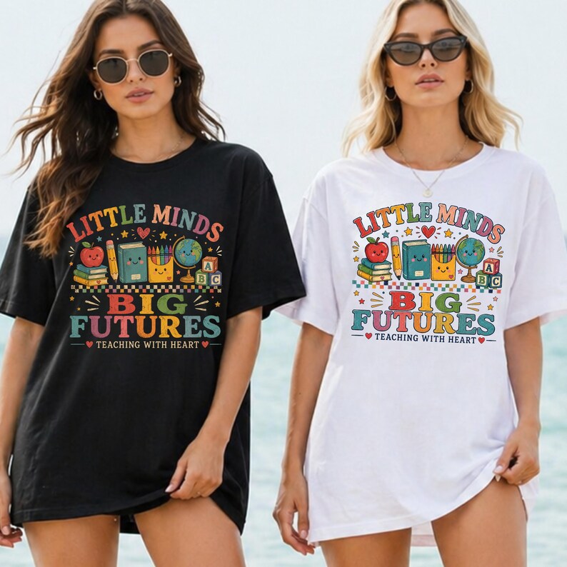 Peut inclure: Un t-shirt noir et un t-shirt blanc, chacun arborant un imprim&eacute; graphique color&eacute; avec le texte "LITTLE MINDS BIG FUTURES TEACHING WITH HEART" et des illustrations d'une pomme, de livres, de crayons, d'un globe et de cubes alphabet.