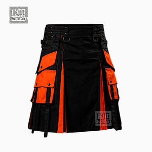 Puede incluir: Una falda escocesa utilitaria negra y naranja con múltiples bolsillos cargo, anillos en D de metal y correas ajustables. La prenda muestra el logotipo de Kilt Outfitters en las esquinas superior izquierda e inferior derecha. Incluye pliegues.