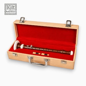 Puede incluir: Una flauta dulce de madera marrón con detalles blancos descansa dentro de un estuche de madera clara forrado con terciopelo rojo. El estuche tiene un asa y cierres plateados. También se ven dos lengüetas. El logotipo "Kilt Outfitters" está en la esquina superior izquierda.