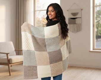 May include: A rectangular knit blanket featuring a patchwork design of alternating squares in shades of cream, beige, taupe, and light gray. The squares display various textures, including diagonal ribbing, seed stitch, and vertical ribbed patterns.