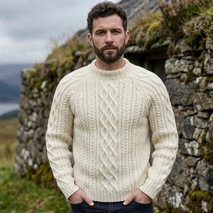 May include: An off-white, long-sleeved crew neck sweater featuring a prominent cable knit pattern on the front. The garment is constructed with a ribbed collar, ribbed cuffs, and a ribbed hem, showcasing a thick, textured knit design throughout.