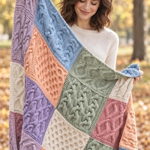 May include: A multi-colored knitted blanket featuring a patchwork design of various cable knit patterns. The squares are colored in shades of lavender, light blue, peach, sage green, and cream, creating a textured and geometric appearance.