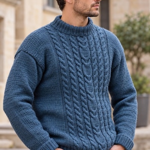 May include: A blue long-sleeve jumper featuring a mock neck collar and a vertical cable knit pattern on the front panel. The garment has ribbed cuffs and a ribbed hem, with plain knit sleeves and side panels in a matching blue yarn.