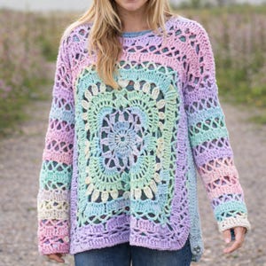 May include: A pastel-colored crochet sweater with a square, floral-patterned front panel. The sweater features a crew neck and long sleeves, with a gradient of colors including pink, blue, green, and purple. The crochet design has openwork details.