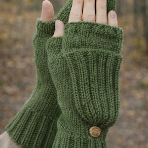 Peut inclure: Mitaines vertes tricotées avec un bouton. Les gants sont de couleur verte unie et ont un poignet côtelé et un rabat qui recouvre les doigts. Les gants sont faits d'une matière douce et chaude.