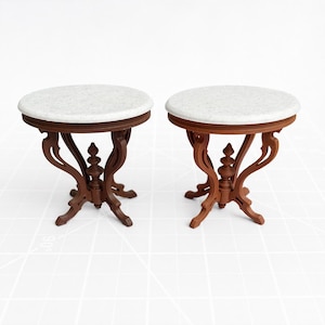 May include: Two miniature round tables with white tops and ornate brown wooden legs. The tables have a classic design, with a circular tabletop and detailed, curved legs. Each table is approximately 3 inches in diameter.