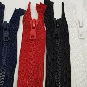 May include: Close-up of four zippers in navy blue, red, black, and white. Each zipper is closed, showing the teeth and pull tab. The zippers are made of a durable material and are suitable for various sewing projects.