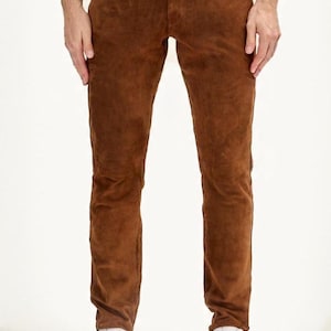 Könnte beinhalten: Braune Wildlederhose mit klassischem Fünf-Taschen-Design. Die Hose hat einen geraden Beinverlauf und wird mit weißen Turnschuhen kombiniert. Das Wildledermaterial hat ein weiches, strukturiertes Aussehen.