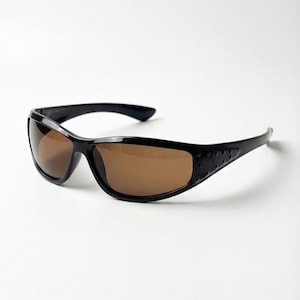 Peut inclure: Lunettes de soleil noires avec des verres bruns. Les lunettes de soleil ont un design élégant et sportif avec une monture incurvée et un détail texturé sur les branches. Les verres sont de couleur marron chaud.
