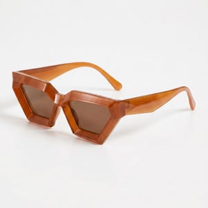 Peut inclure: Lunettes de soleil marron au design géométrique et angulaire. Les montures et les verres sont de la même teinte marron. Les lunettes de soleil ont un look moderne et élégant.