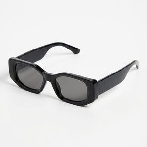 May include: Black rectangular sunglasses with dark gray lenses. The sunglasses have a thick, glossy frame and a classic, modern design. The arms curve slightly for a comfortable fit. A stylish accessory for eye protection.