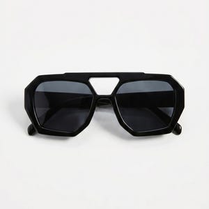 May include: Black sunglasses with a geometric, angular design. The sunglasses have a thick, black frame with a bridge and dark lenses. The shape is a modern take on a classic style, suitable for various face shapes.