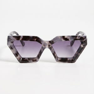 May include: Angular sunglasses with a marbled grey and black frame and gradient purple lenses. The sunglasses have a distinctive geometric shape, providing a modern and stylish appearance. Ideal for adding a touch of flair to any outfit.