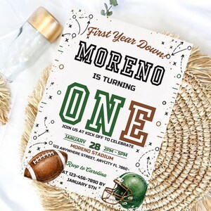 Könnte beinhalten: Eine rechteckige Geburtstagseinladungskarte mit Football-Motiv. Der Text lautet First Year Down, MORENO IS TURNING ONE, JOIN US AT KICK OFF TO CELEBRATE, JANUARY 28 2PM-5PM, MORENO STADIUM, 123 ANYWHERE STREET, ANYCITY FL 7850, RSVP to Carolina AT 123-456-7890 BY JANUARY 5TH. Sie zeigt eine Illustration eines braunen Footballs und eines grünen Footballhelms.