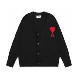 Puede incluir: Cárdigan negro con cuello en V y cierre de botones. Presenta un corazón rojo y el logo "A" en el pecho izquierdo. El suéter tiene mangas largas y una pequeña etiqueta blanca cerca del cuello.