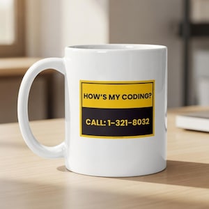 Può includere: Tazza in ceramica bianca con un manico grande. La tazza presenta un design rettangolare giallo e nero con il testo "HOW'S MY CODING?" e "CALL: 1-321-8032". La tazza è su una superficie di legno chiaro.