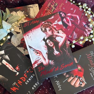 May include: A collection of five books from The Mindf*ck Series by S.T. Abby, featuring illustrated covers with dark, dramatic themes including knives, blood, and apples. The books are arranged together with white floral accents on a dark fabric.