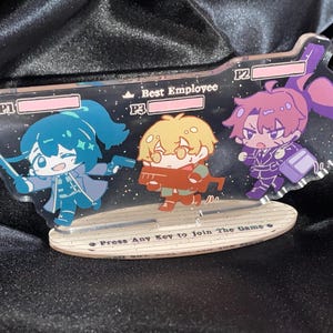 Puede incluir: Un expositor de acrílico transparente con tres personajes de estilo chibi en una interfaz de videojuego. Los personajes están etiquetados como P1, P3 y P2, con el texto Best Employee y Press Any Key to Join The Game en la base.