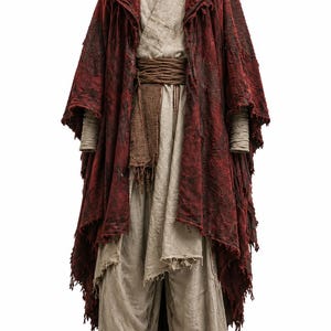 May include: A layered outfit consisting of a deep red, distressed hooded cloak with frayed edges worn over a beige, textured tunic and matching loose-fitting trousers. A dark brown, multi-wrapped fabric belt cinches the waist of the ensemble.